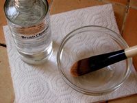 makeup brush in cleaning solution next to bottle