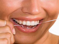 person smiling while flossing teeth