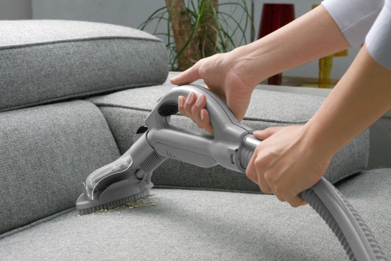 How To Clean A Couch A Person Vacuuming Grey Sofa