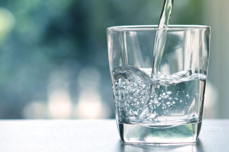 A tumblr glass being filled with water.